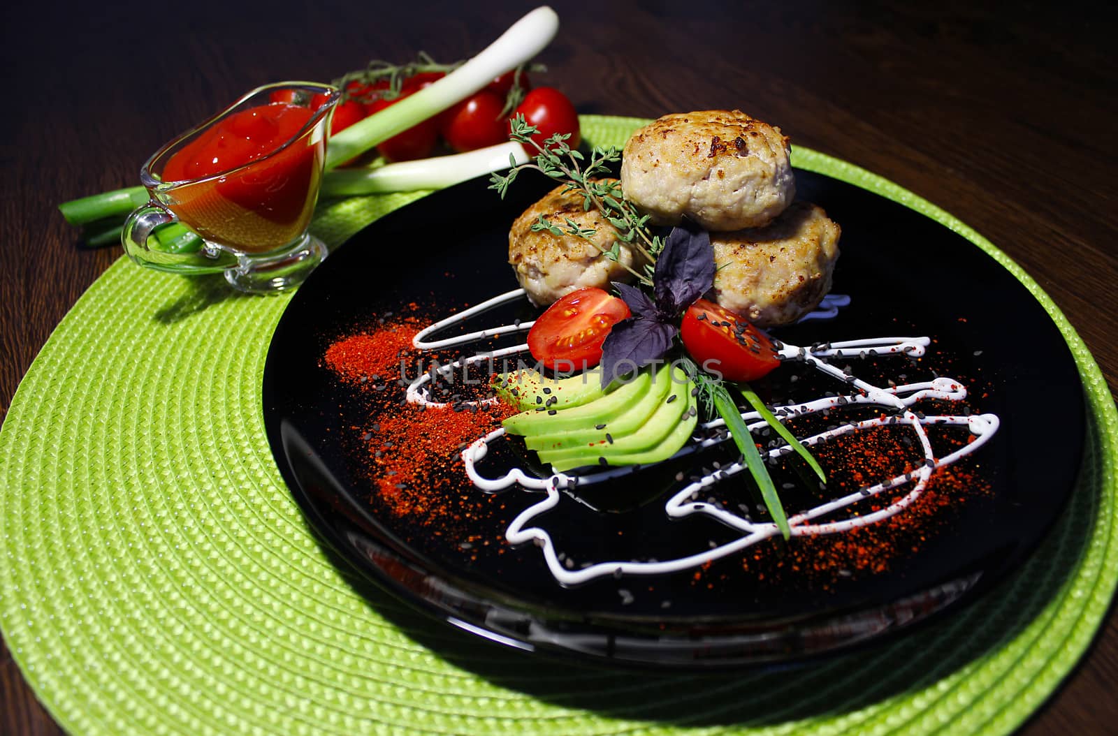 A decorated dish with fried cutlets tomatoes and zucchini slices is served