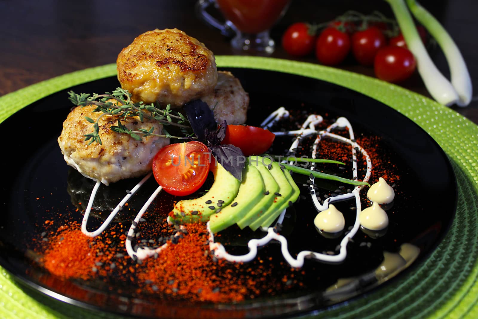 On a plate cutlets with sliced tomatoes zucchini and herbs
