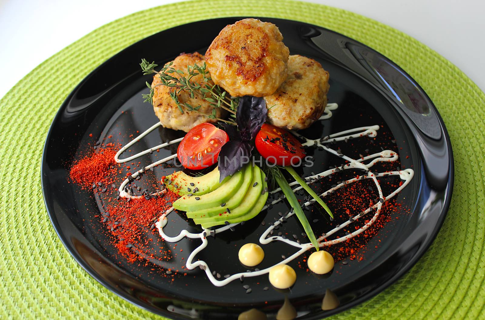 On a plate zucchini with fried cutlets are decorated with mayonnaise and greens with cherry tomatoes