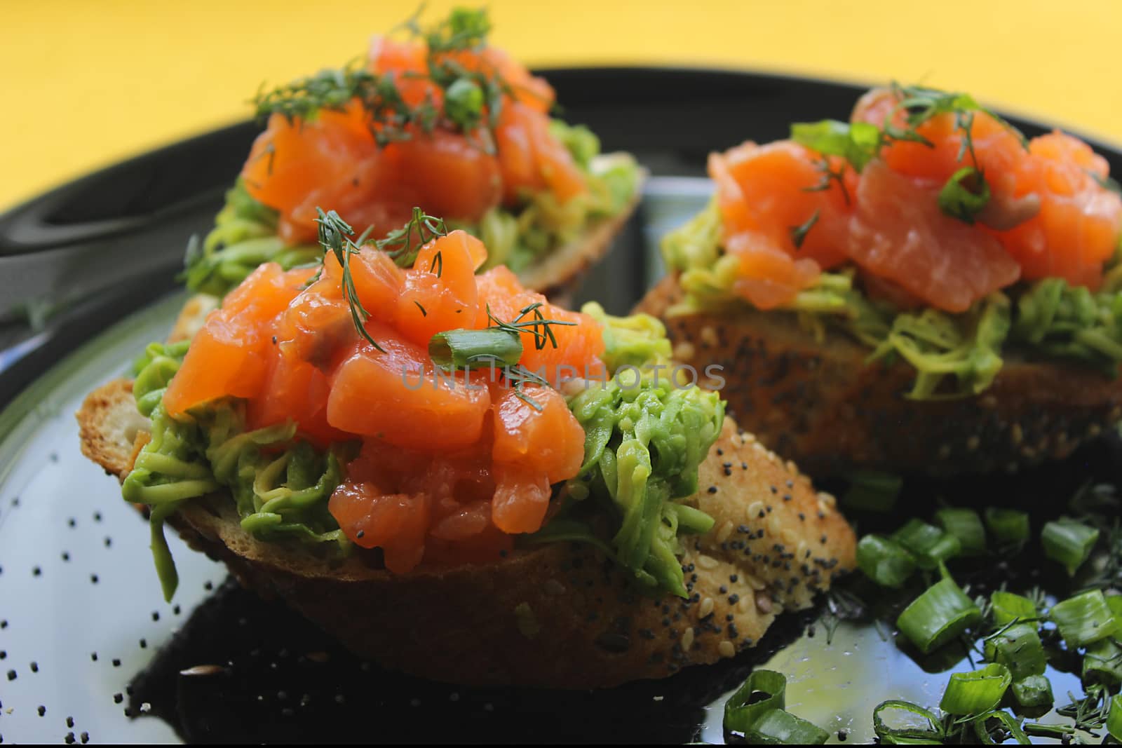 Slices of French baguette with slices of salmon, greens and avocado