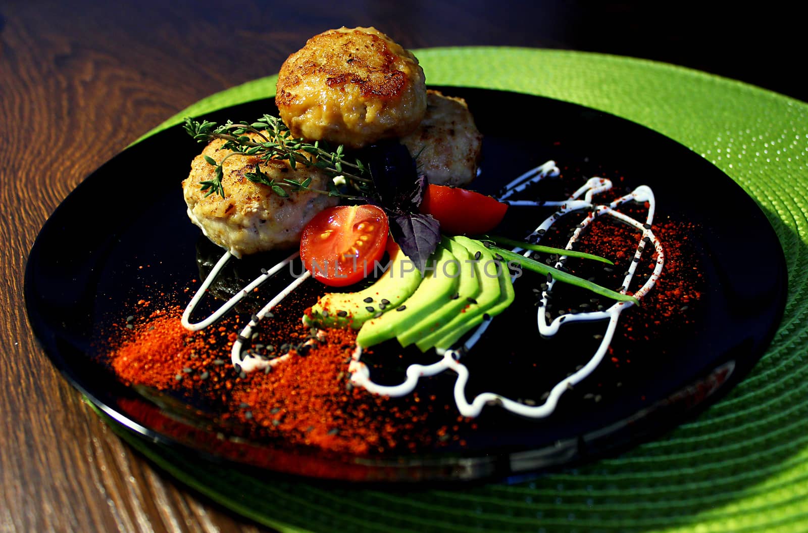 A decorated dish with fried cutlets tomatoes and zucchini slices is served