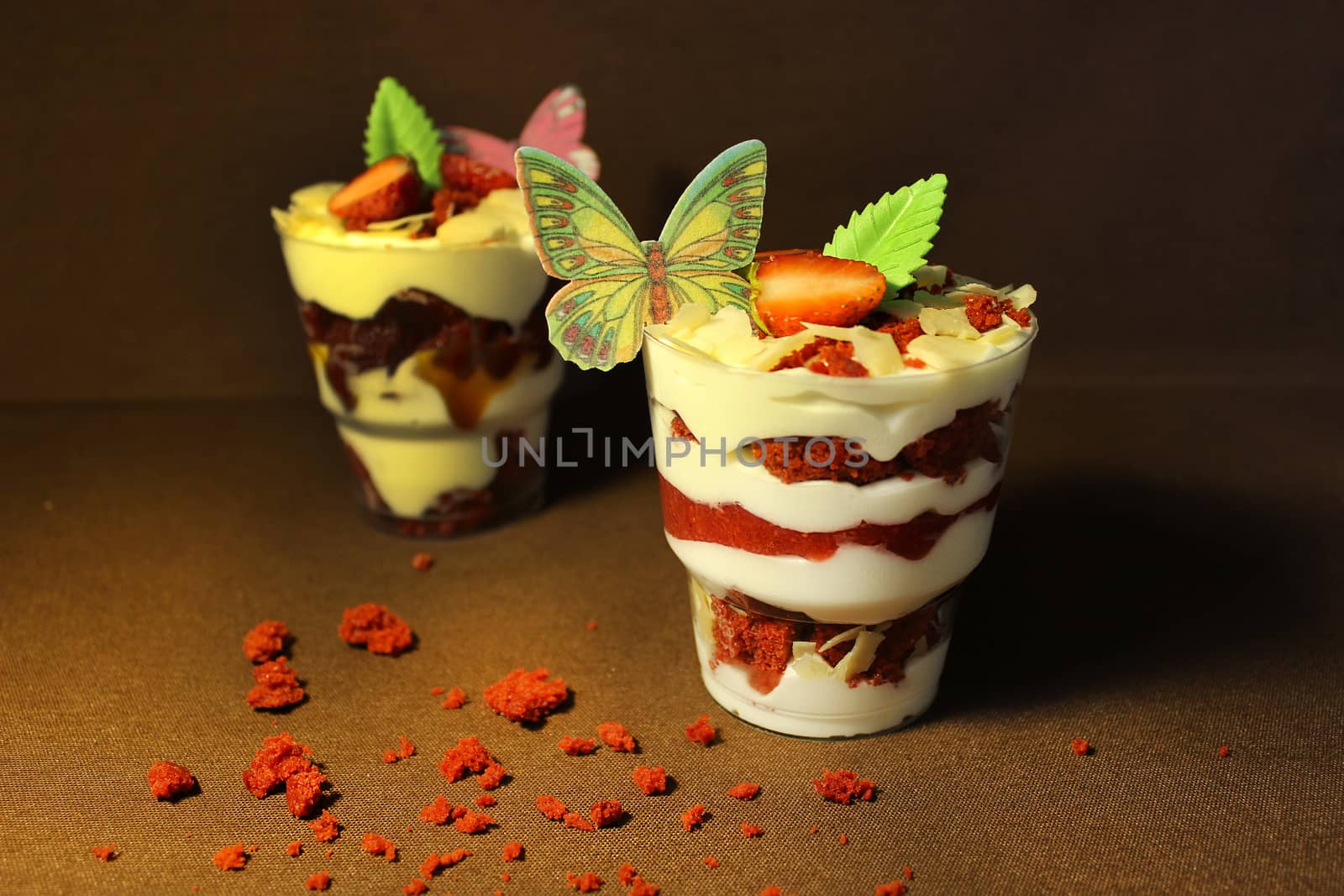 In a transparent container ice cream with a cupcake and a slice of strawberry