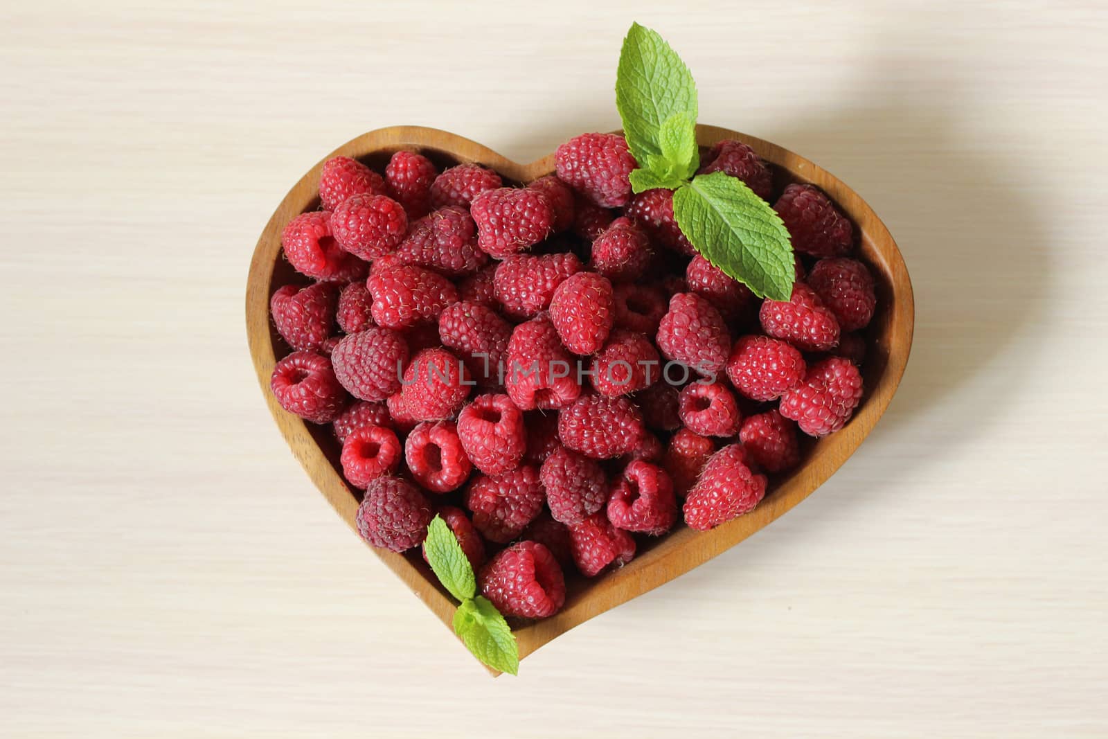 A large handful of sweet raspberries in a wooden container