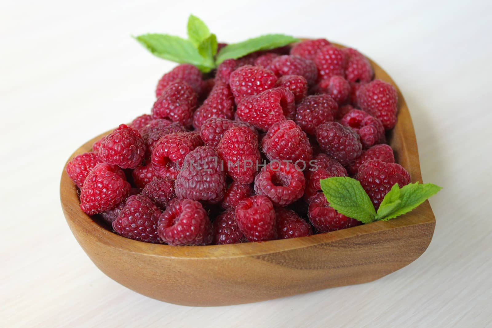 Large quantity of sweet raspberries in a wooden container