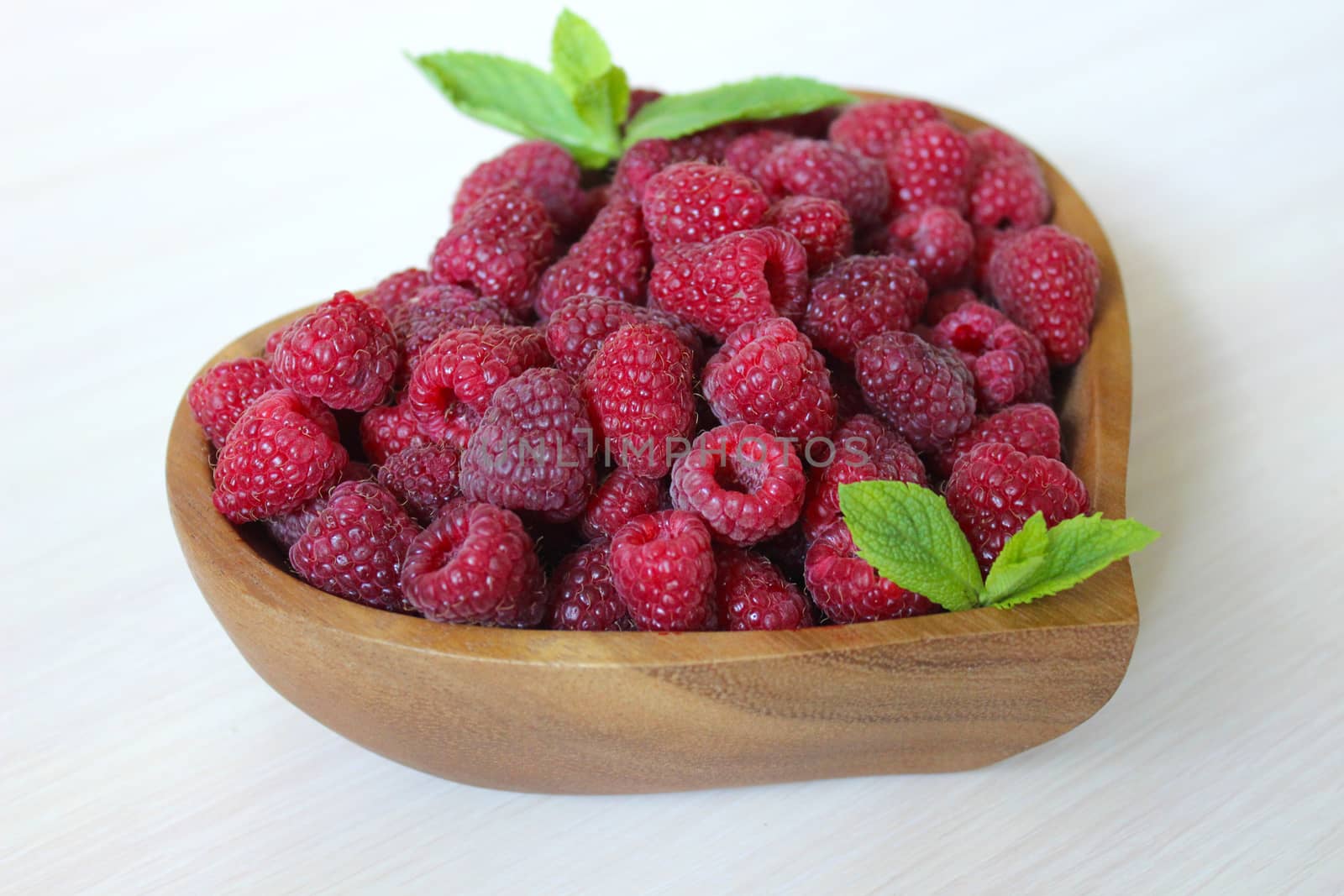 Ripe garden raspberries in a wooden container on the table