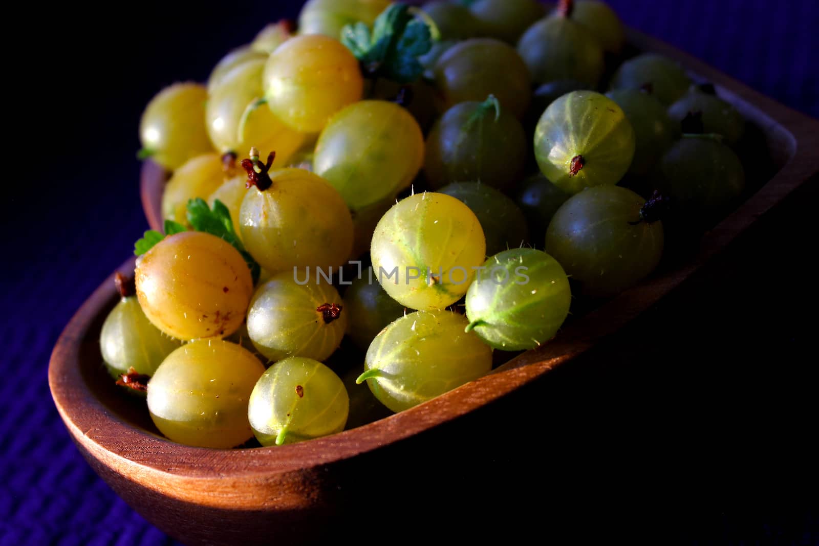 Harvest of gooseberries on a wooden plate.Texture or background