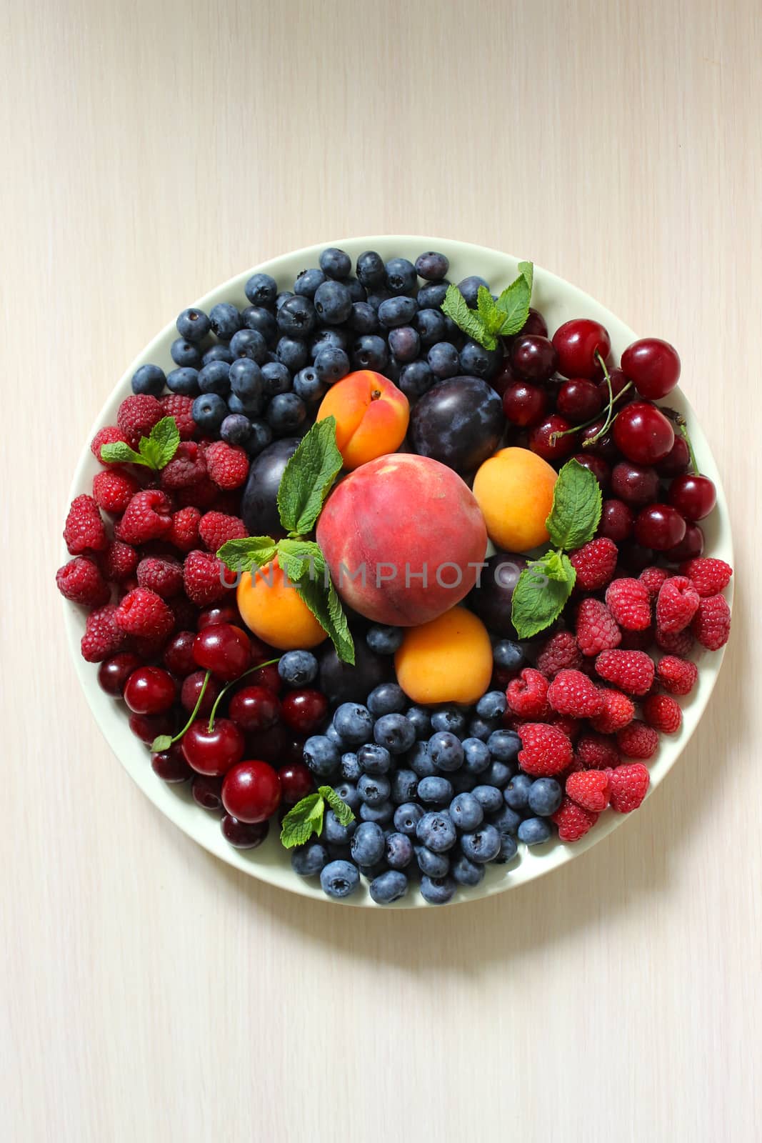 Mix of berries on the table on a white plate .Texture or background