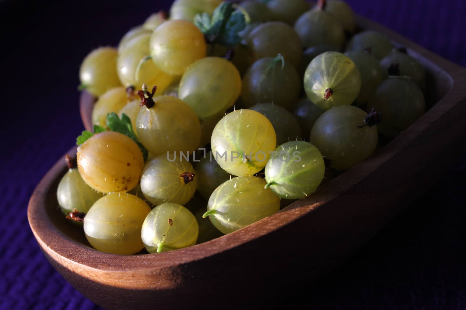 Juicy ripe gooseberries on a wooden plate.Texture or background
