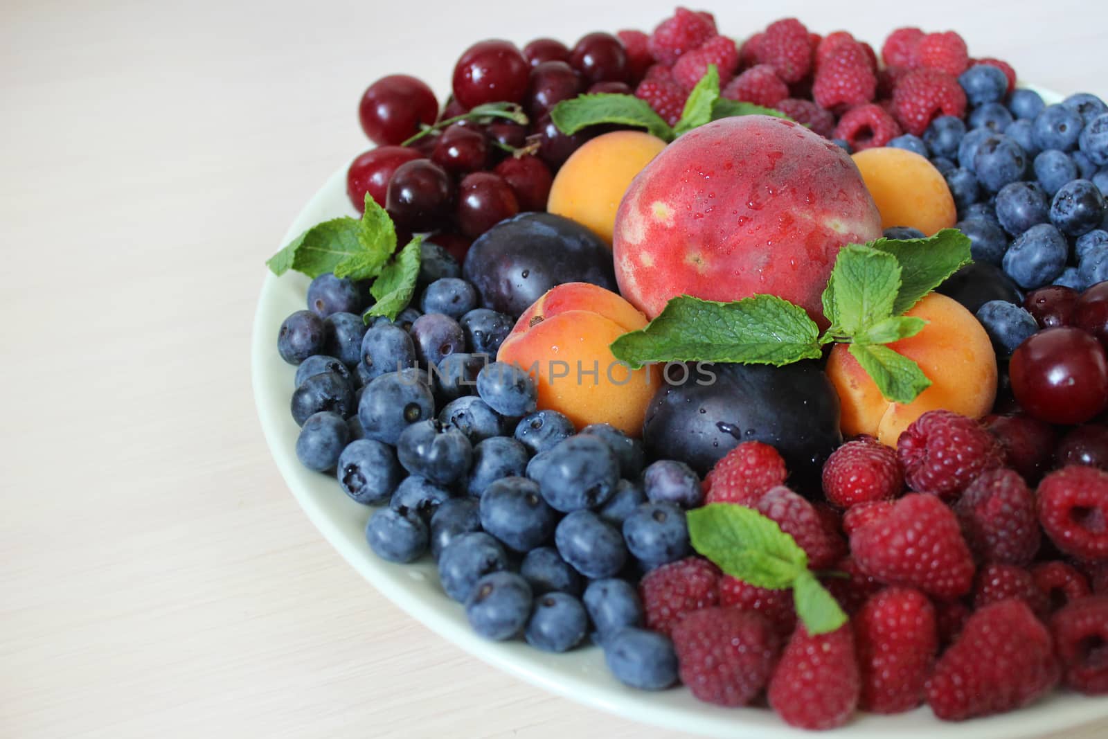 Harvest of ripe berries on a plate on a white background.Texture or background