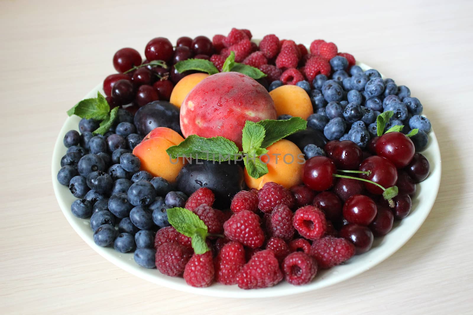 Fresh berry mix on a light background on a white plate .Texture or background