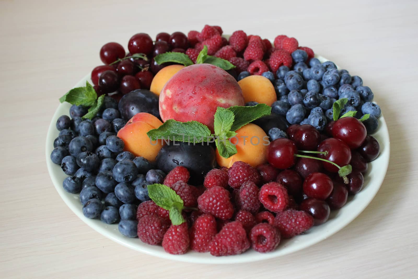Fresh berry mix on a light background on a white plate .Texture or background