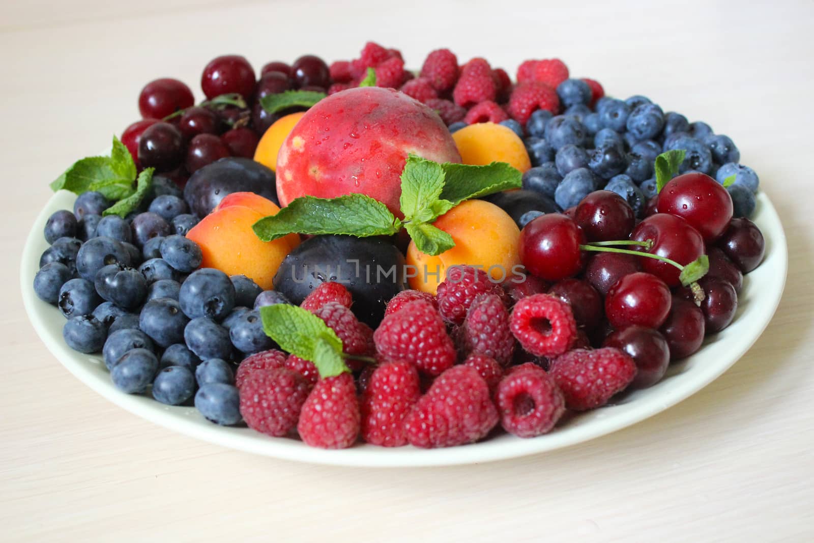 Summer mix of different berries on a light background on a white plate .Texture or background