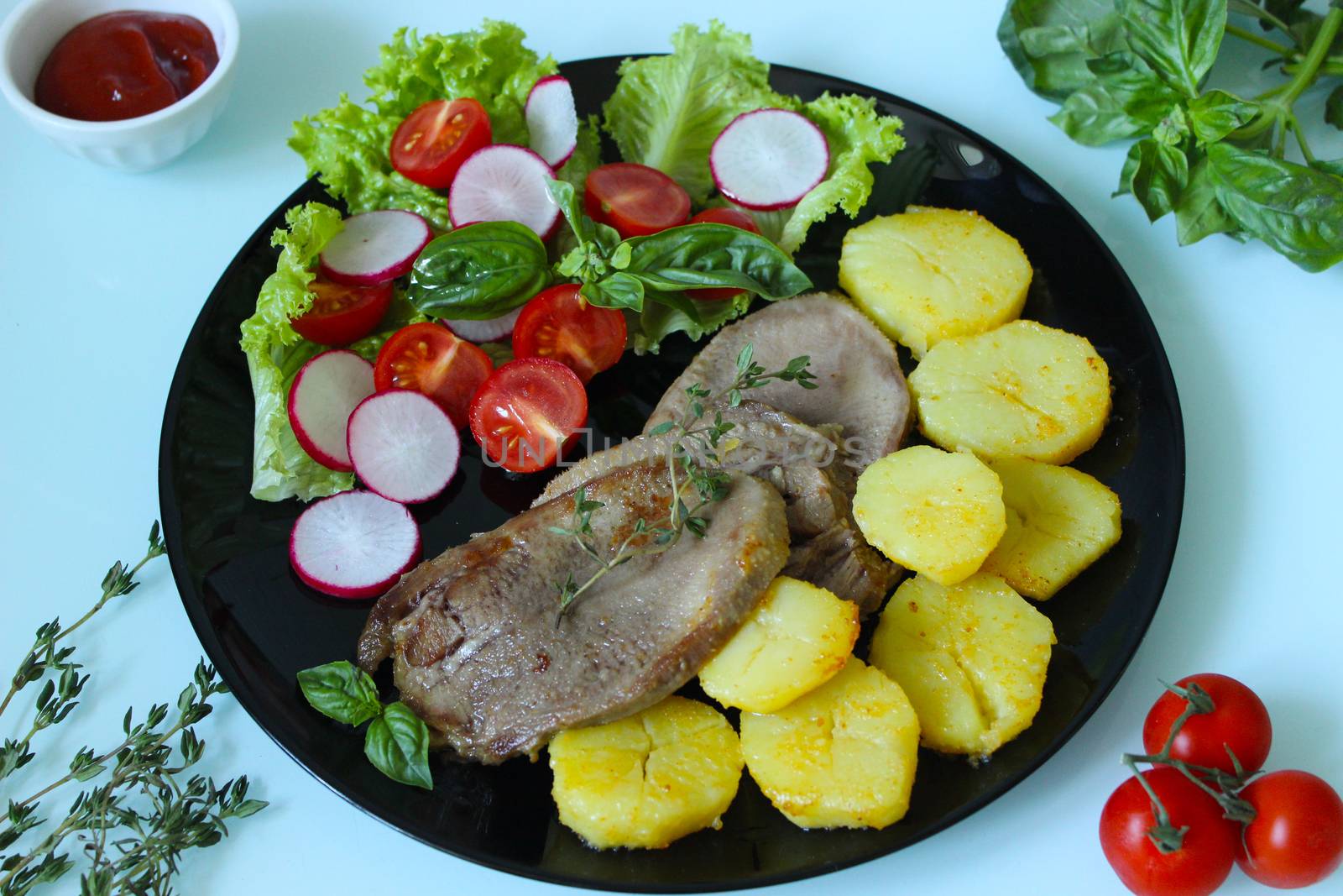 Close up of baked beef tongue with fresh vegetables and potatoes on a black plate