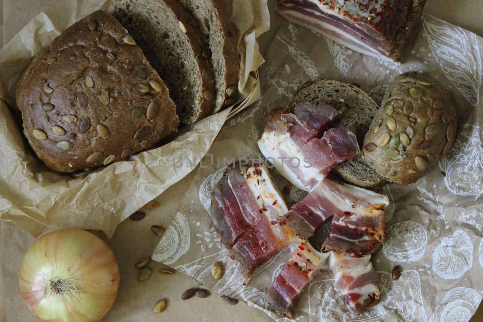On paper slices of bread with slices of bacon and onions close up