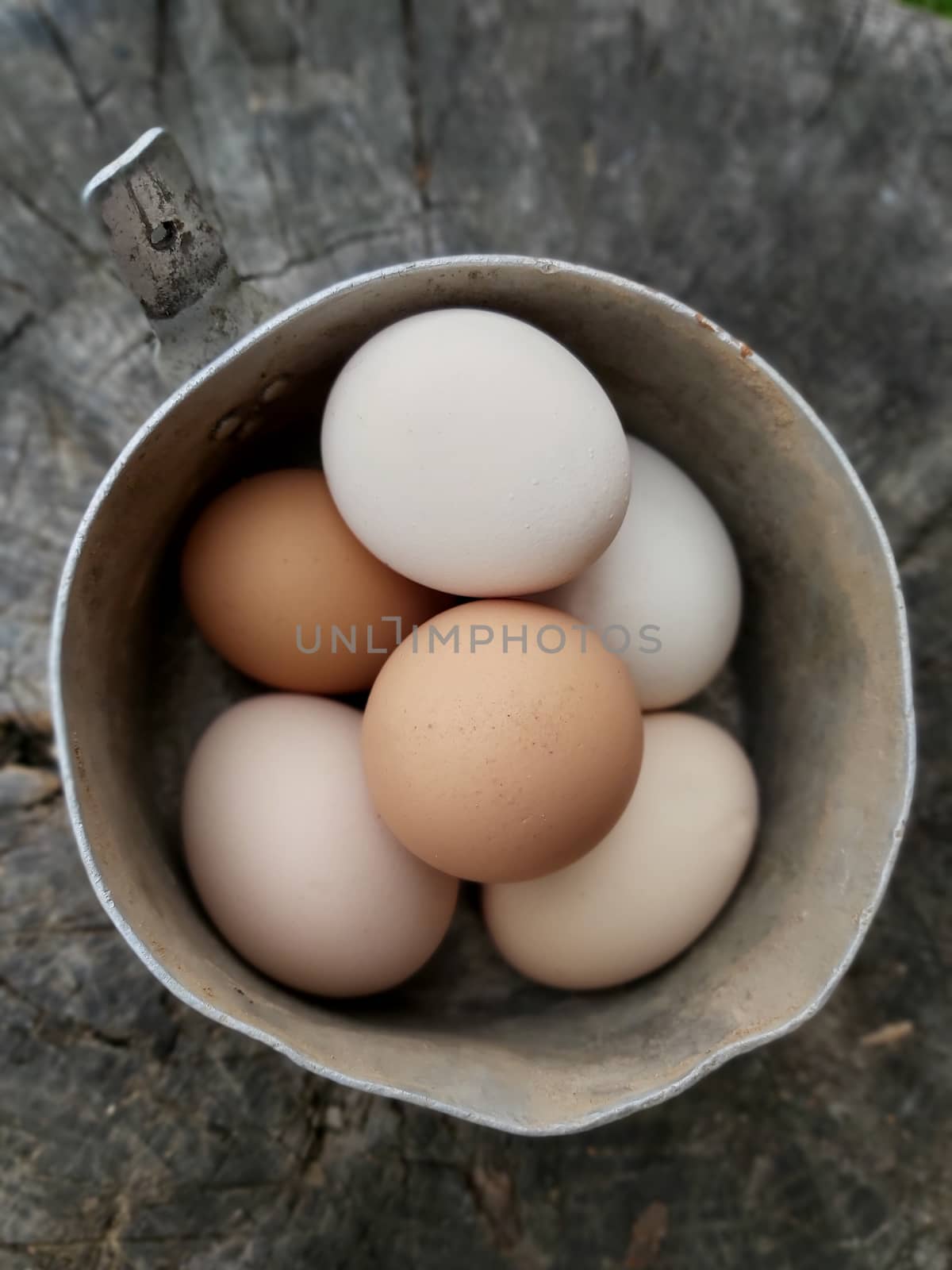 Raw chicken eggs in a pan on a stump .Texture or background