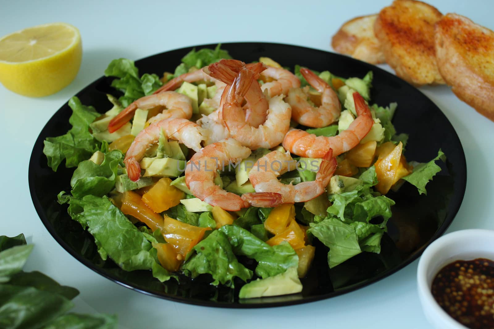 King prawn salad with lemon and herbs on a black plate