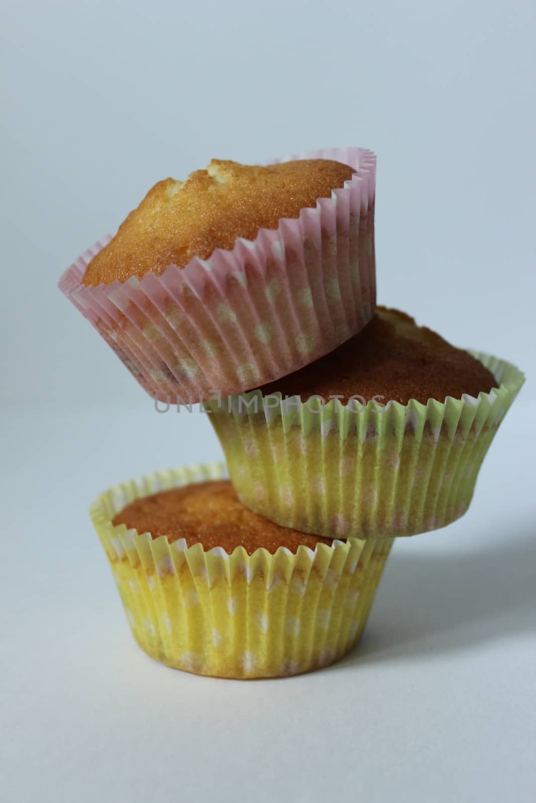 Three cupcakes in a yellow wrapper on a light background .Texture or background