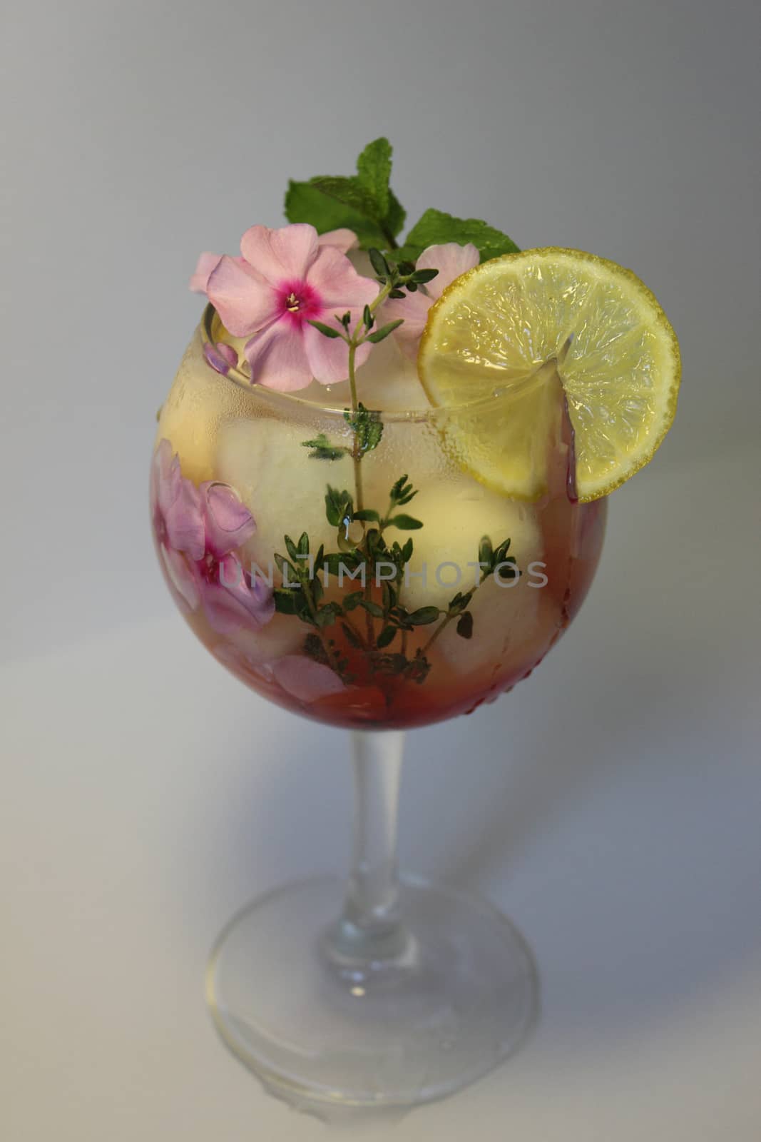 In a clear glass of lemon juice with ice cubes and decorated with flowers close up