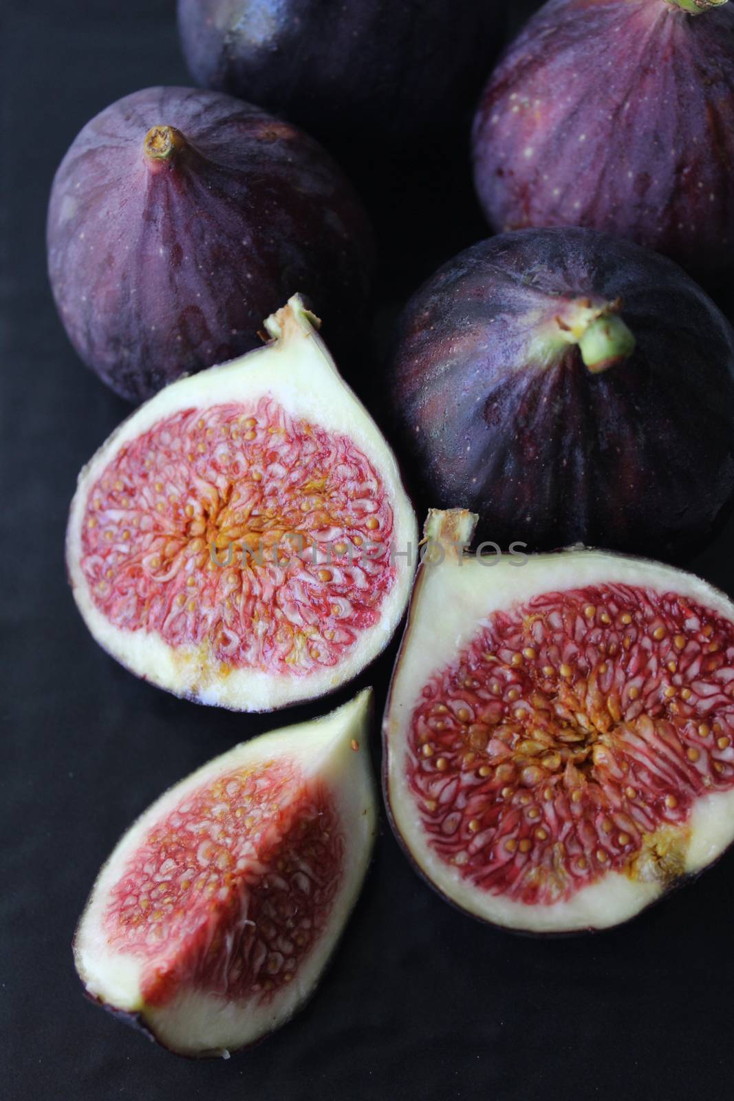 Fig slices are purple on a dark background.Texture or background