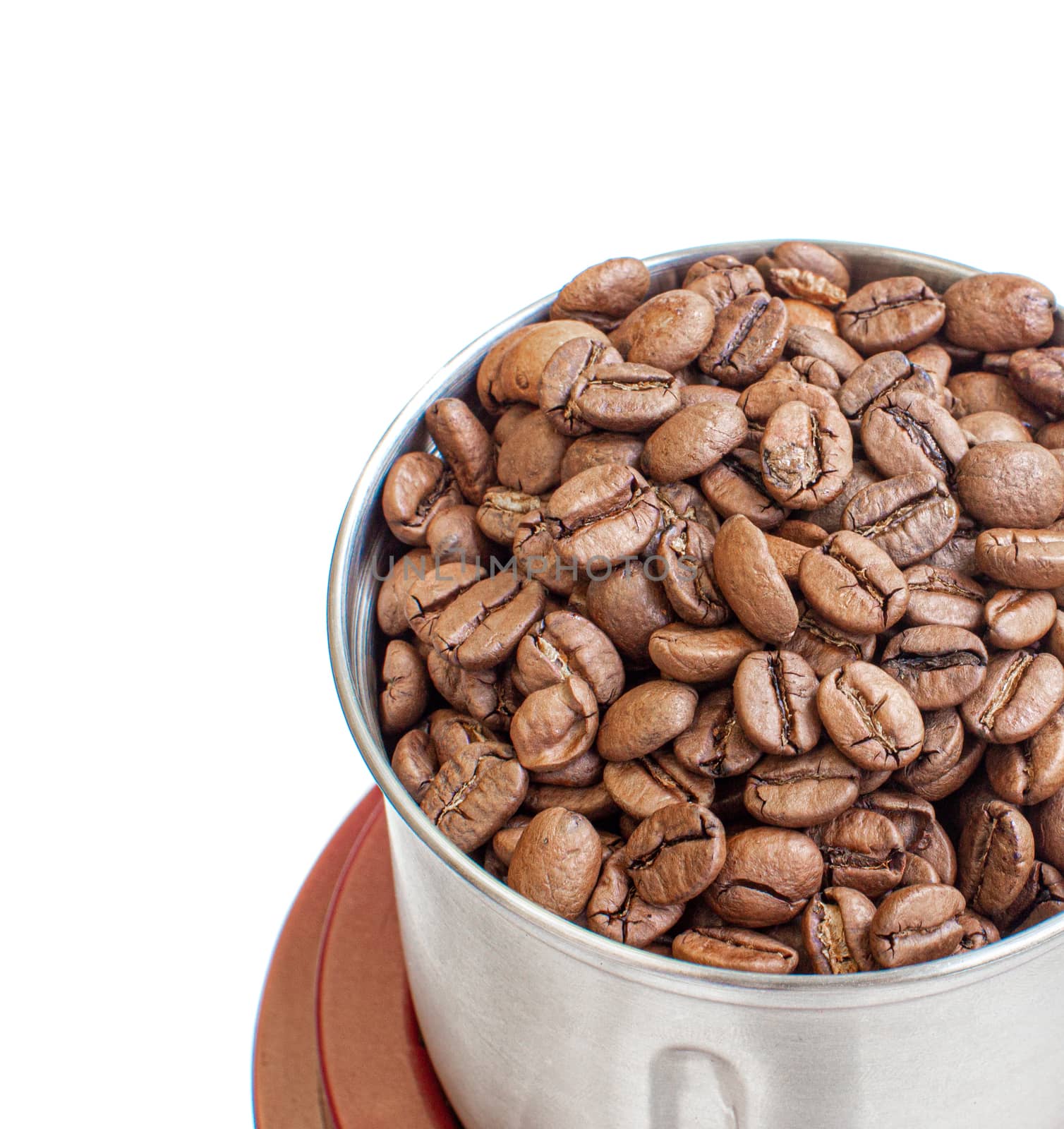 A lot of coffee beans in a metal coffee grinder on a white background. The view from the top. Isolated