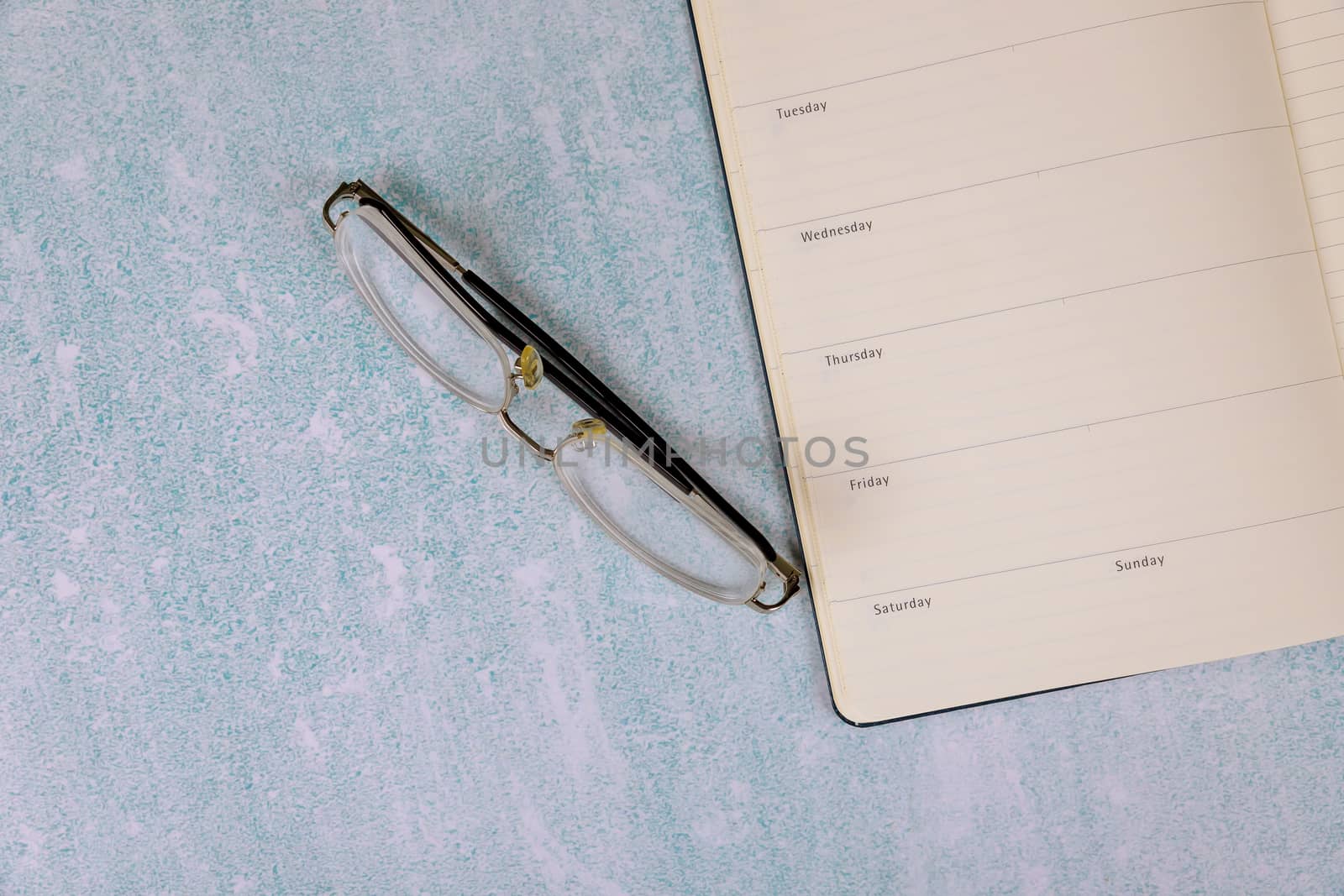 Top view with desk on lined notebook of reading glasses by ungvar