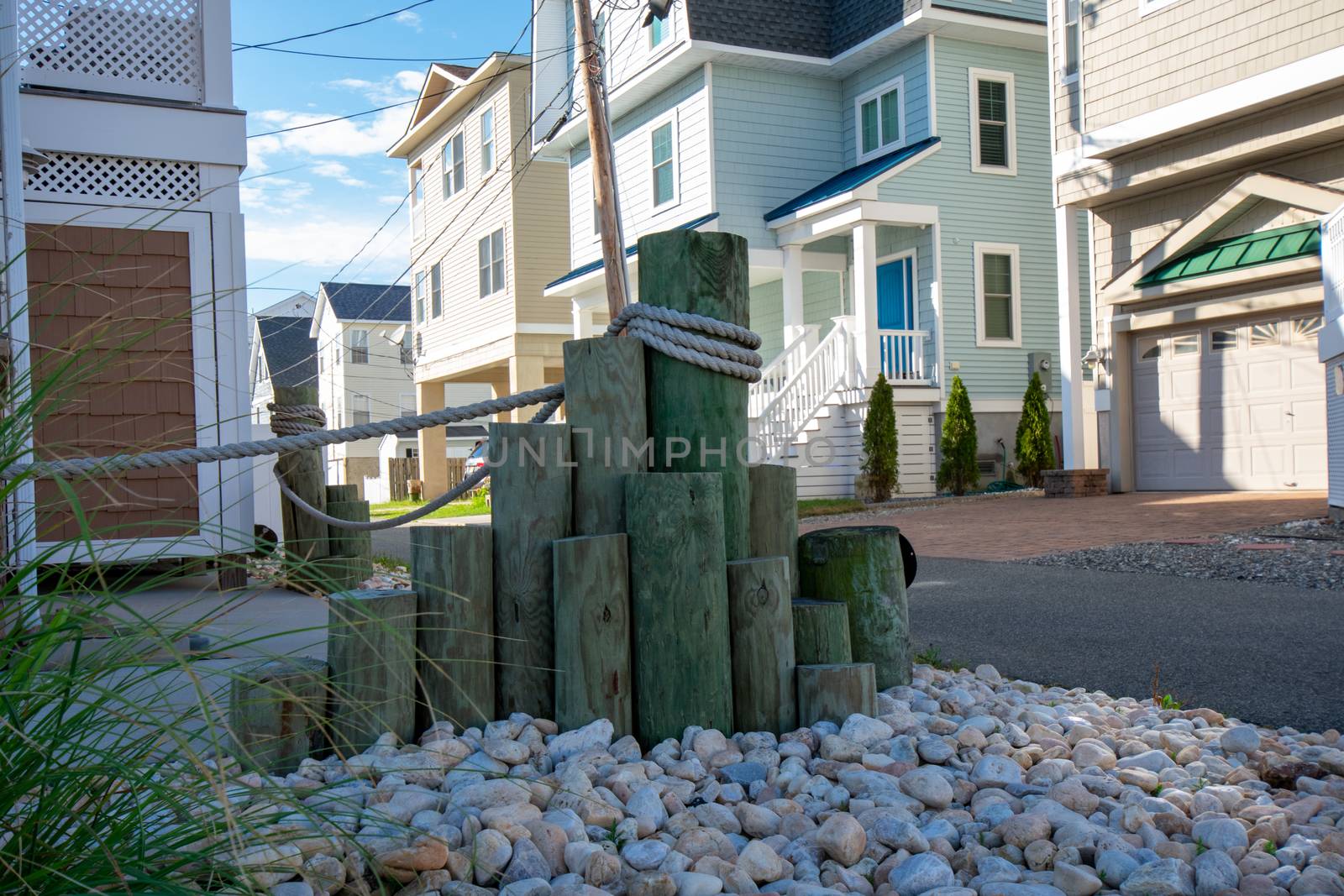 Beach Pilings in a Rock Bed in the Yard of a Shore House by bju12290