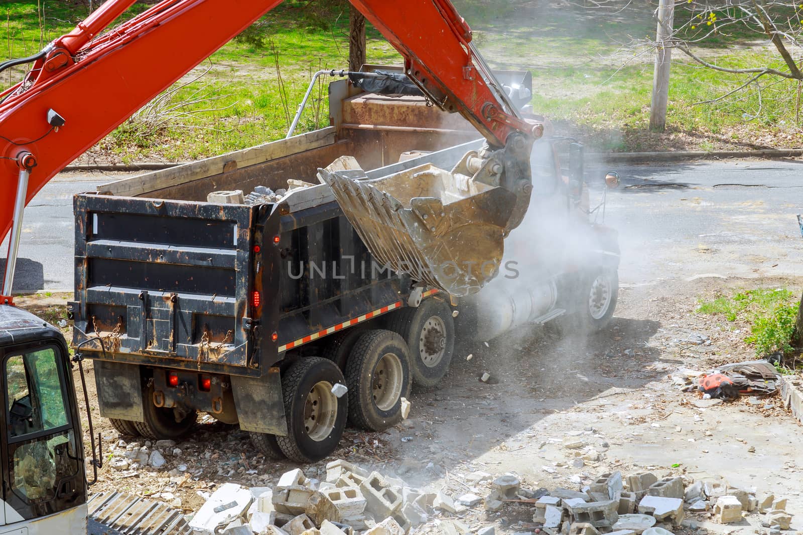 Excavator scoop truck loading a construction waste into reinforced concrete full recycling garbage