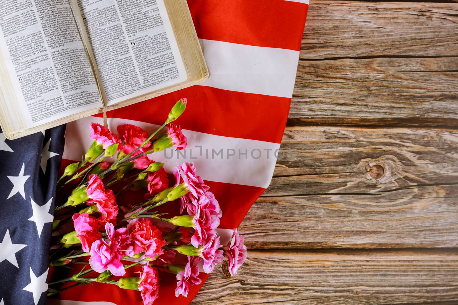 Los Angeles CA US 16 MAY 2020: Carnation flowers on Open reading Holy Bible on a close up of america pray in the American flag