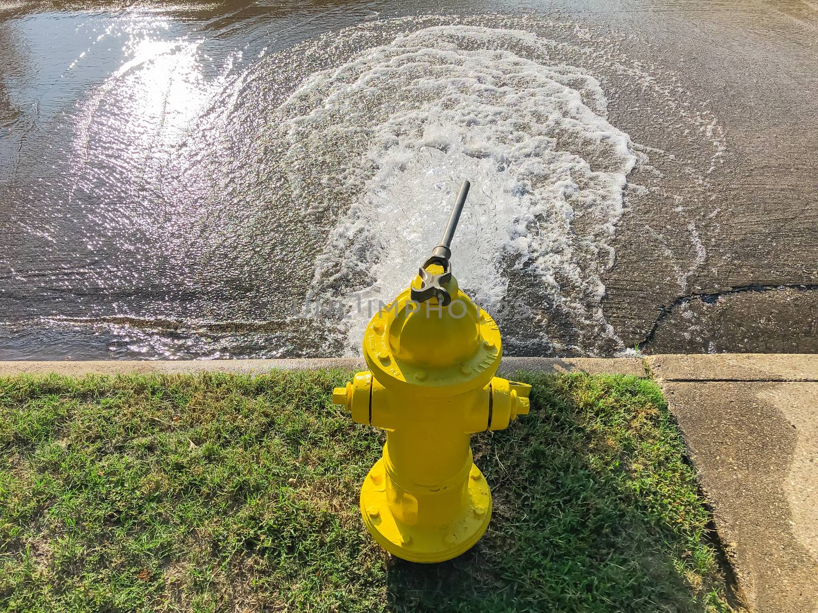 Top view yellow fire hydrant gushing water across a residential street near Dallas, Texas, USA by trongnguyen