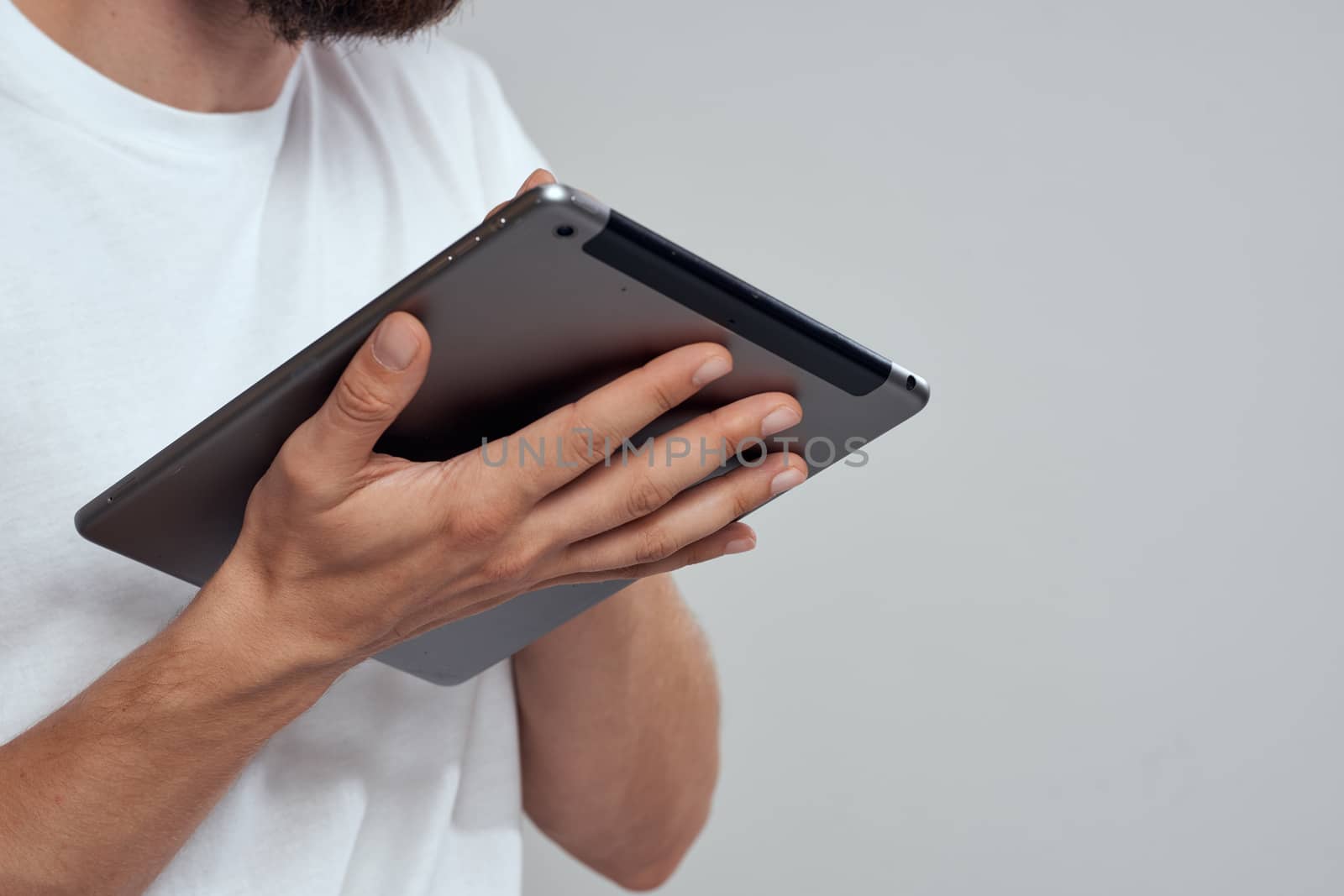 Tablet with a touch screen on a light background male hands white t-shirt cropped view by SHOTPRIME