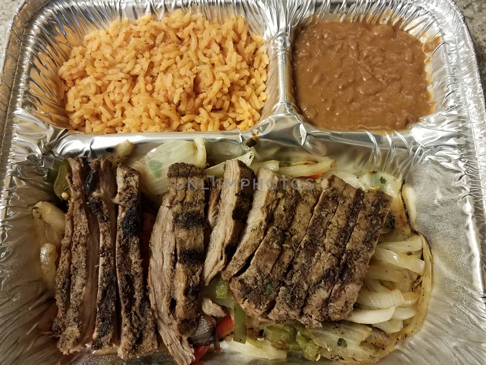 steak fajita meat with rice and beans in metal container or tray