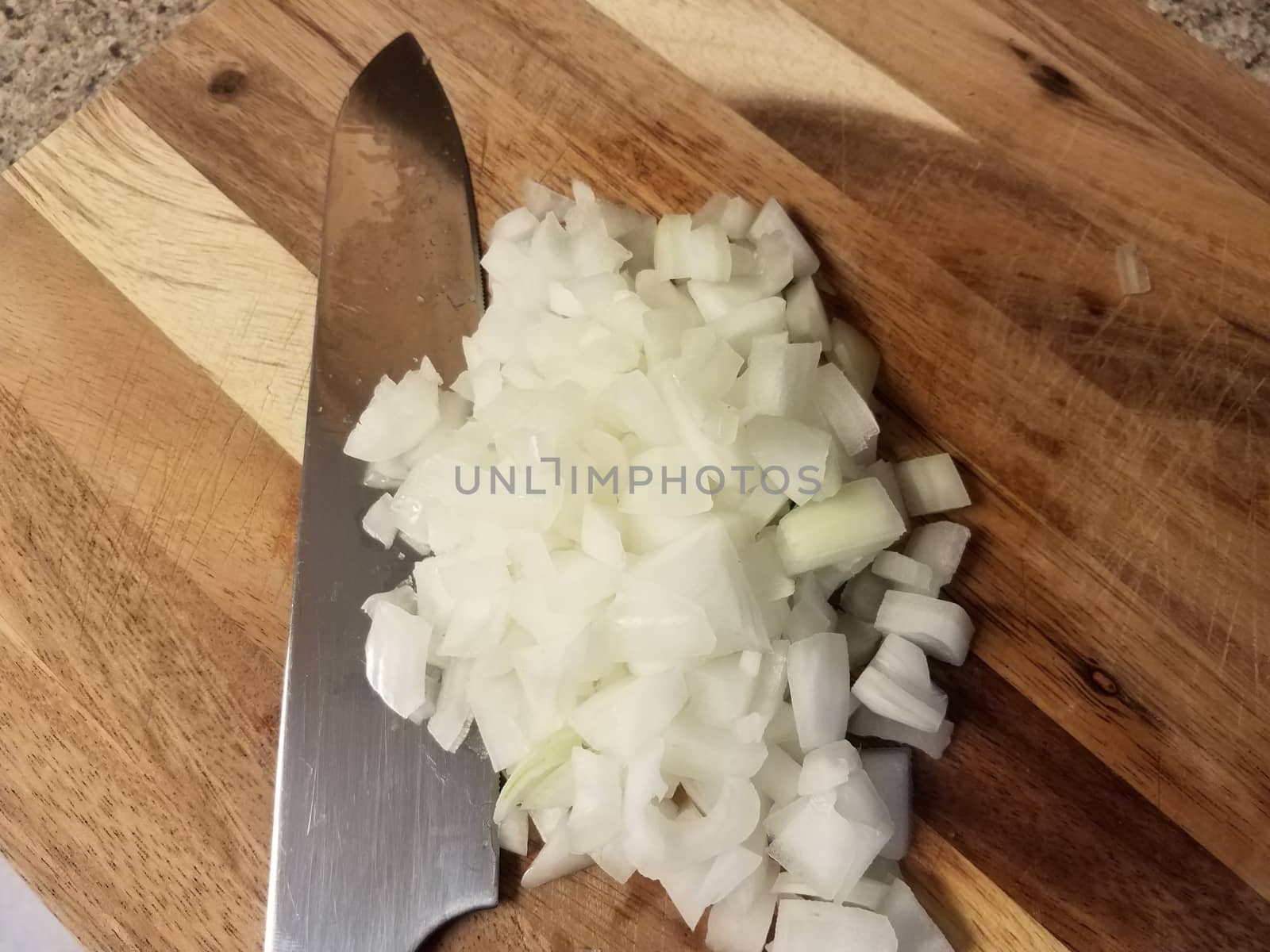 sharp knife on wood cutting board with white onions