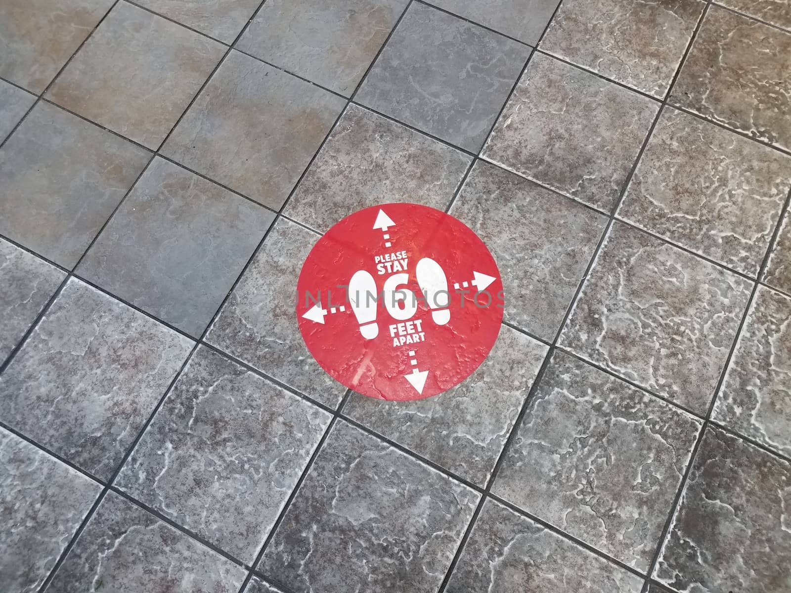 red please stay six feet apart sign on grey tiles on floor
