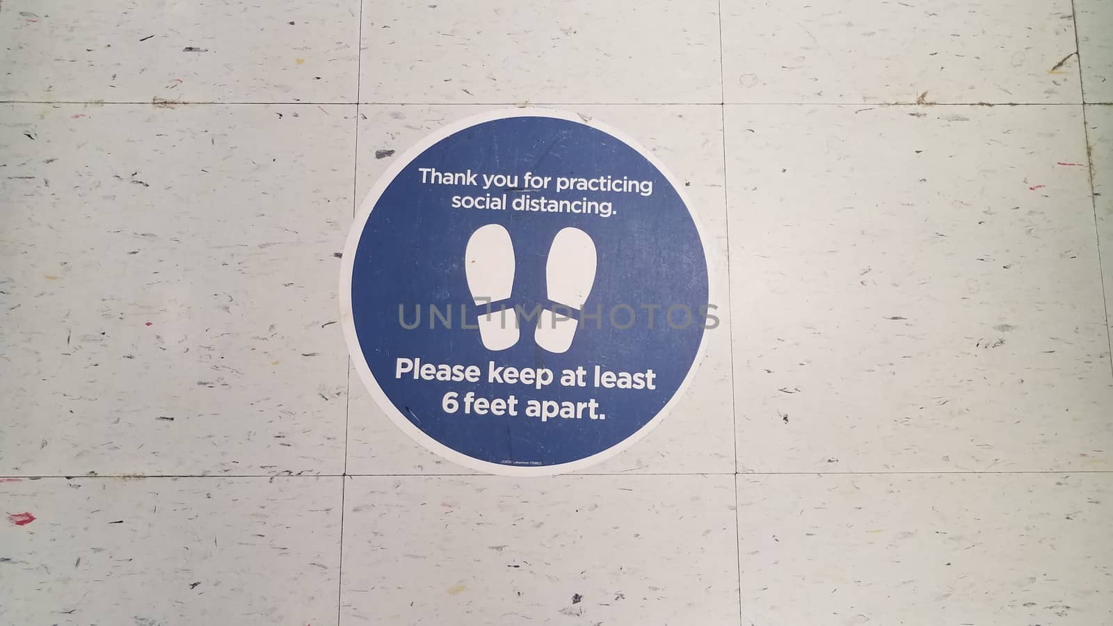 blue please stay six feet apart sign on white tiles by stockphotofan1