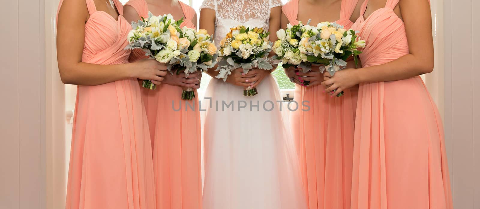 A bride with her bridesmaids all holding their bouquets and posing prior to the wedding ceremony