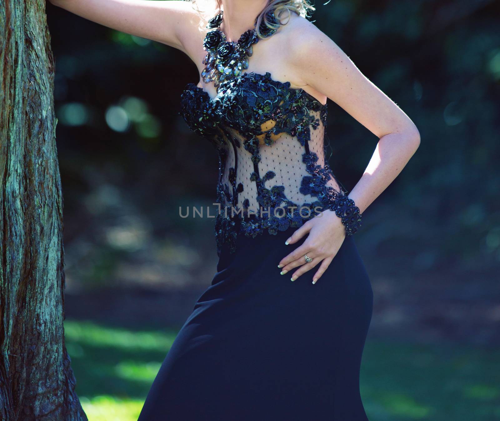 Elegant young woman posing outdoors in an embroidered black dress