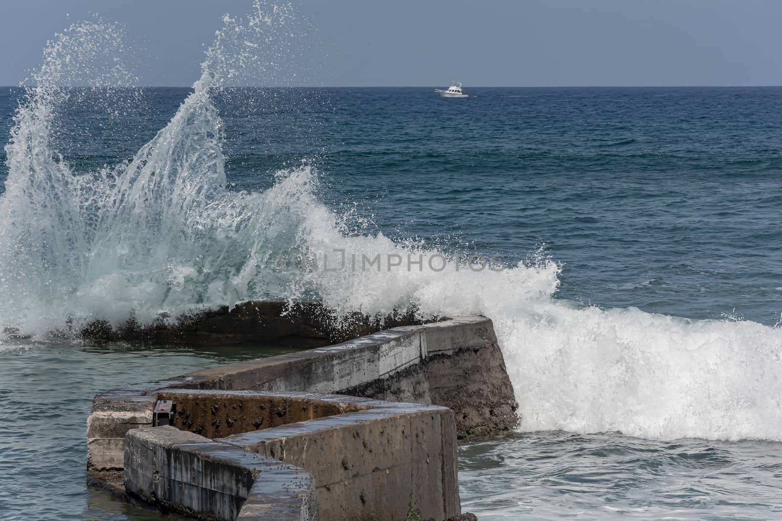 sea wave splashes against a coastal pier. Stock photo
