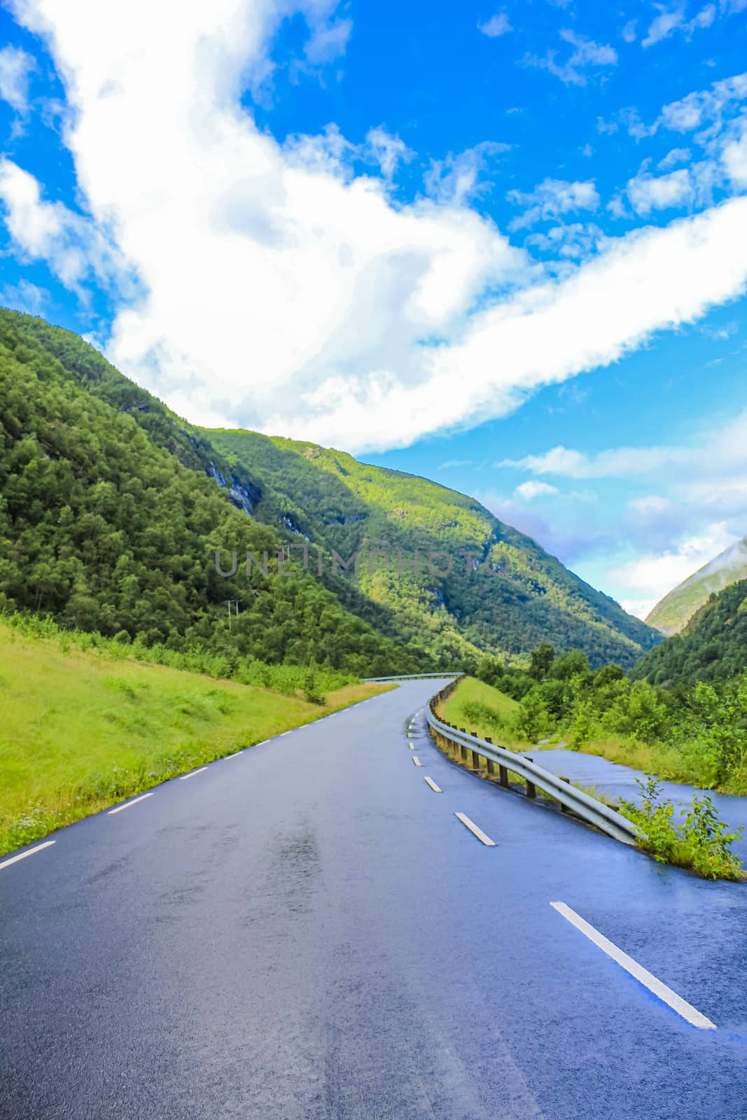 Beautiful wet road the mountains cloudy sky of Hemsedal in Viken, Norway.