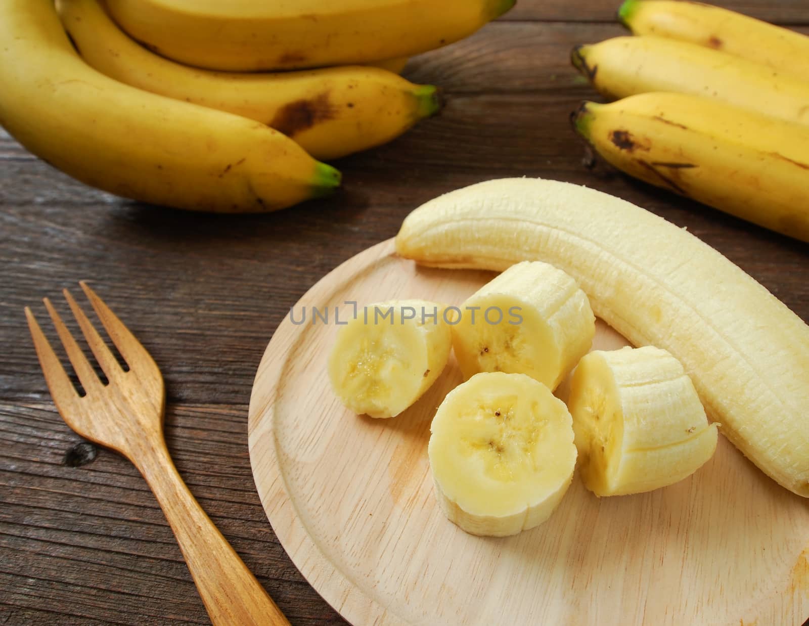 Bananas and banana slices on a plate of wood.