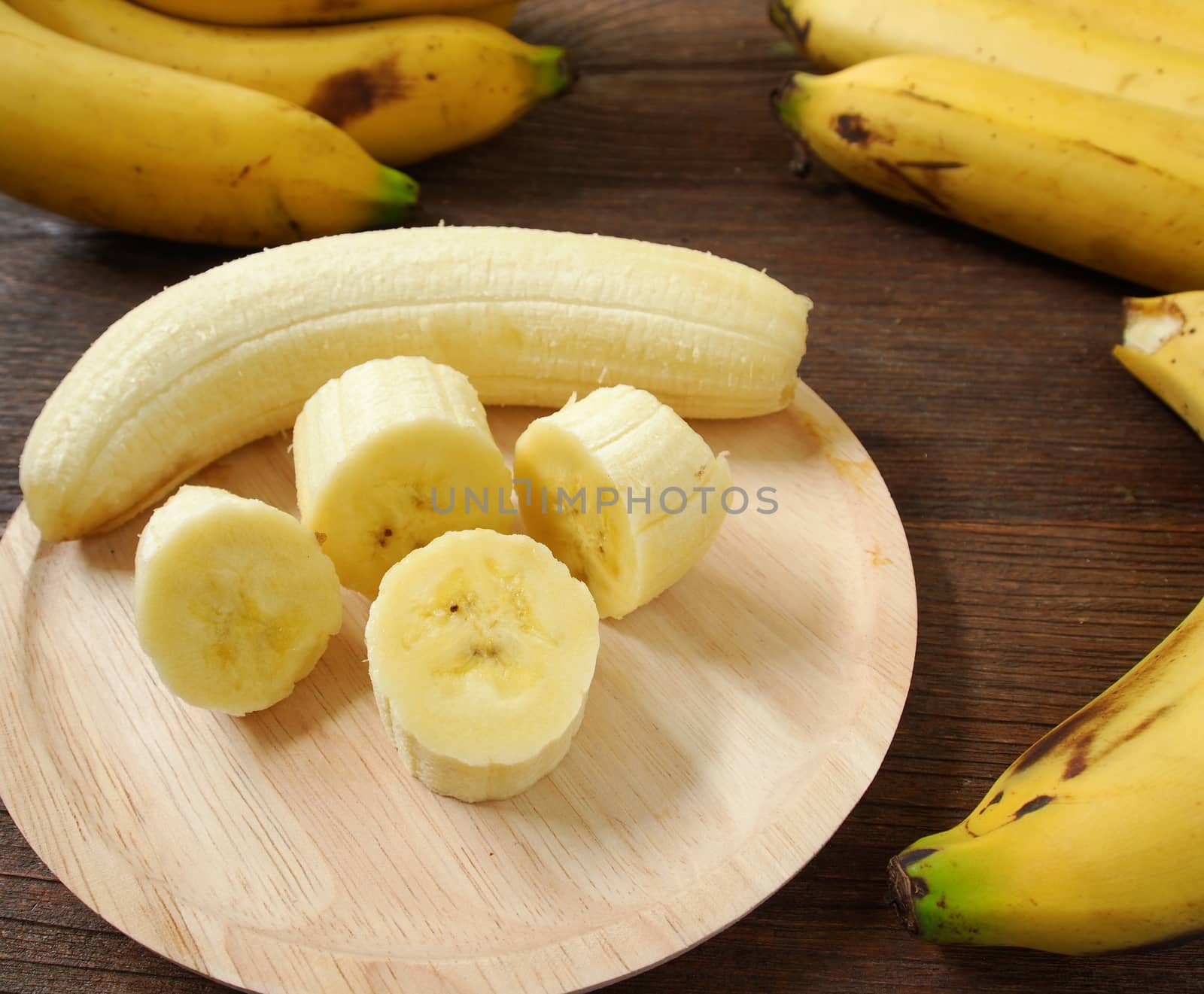 Bananas and banana slices on a plate of wood.