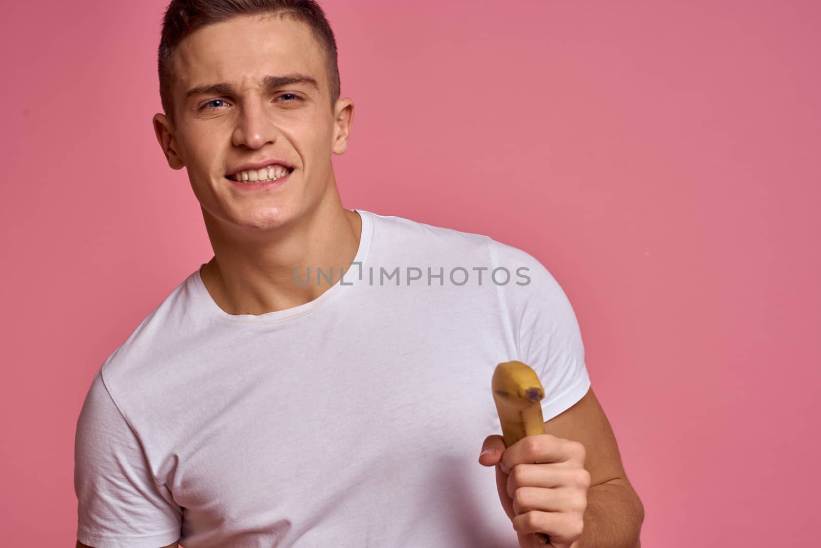 Man with fruits in hands on a pink background healthy food vitamins pink background white t-shirt model. High quality photo