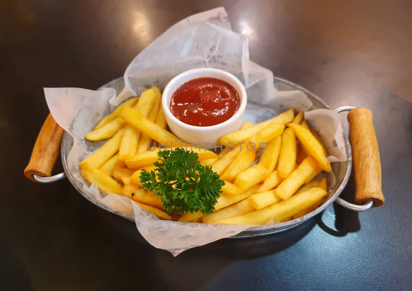 French fries a wooden tray on the dining table by sompongtom