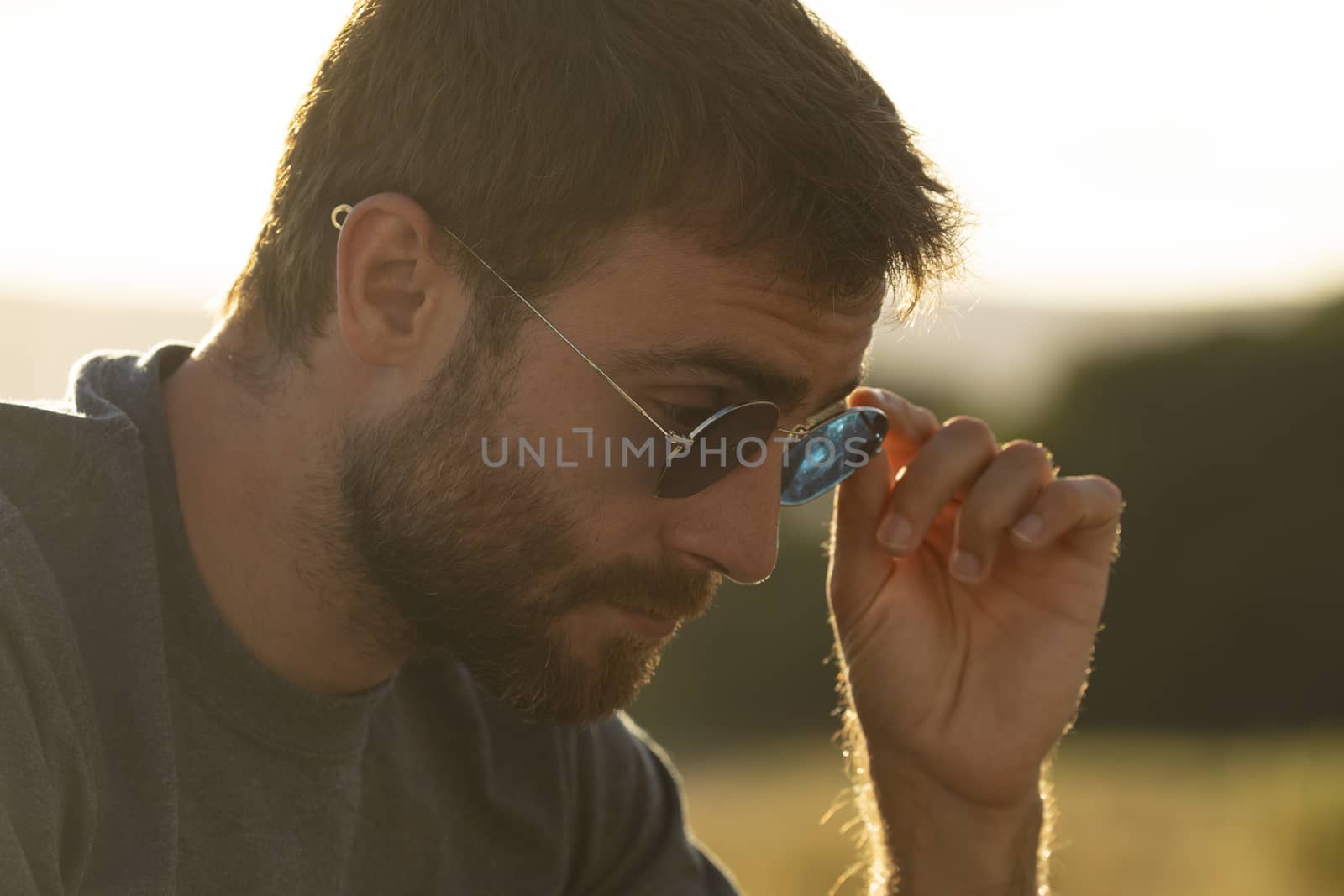 A young man puts on his sunglasses to see better at sunset.