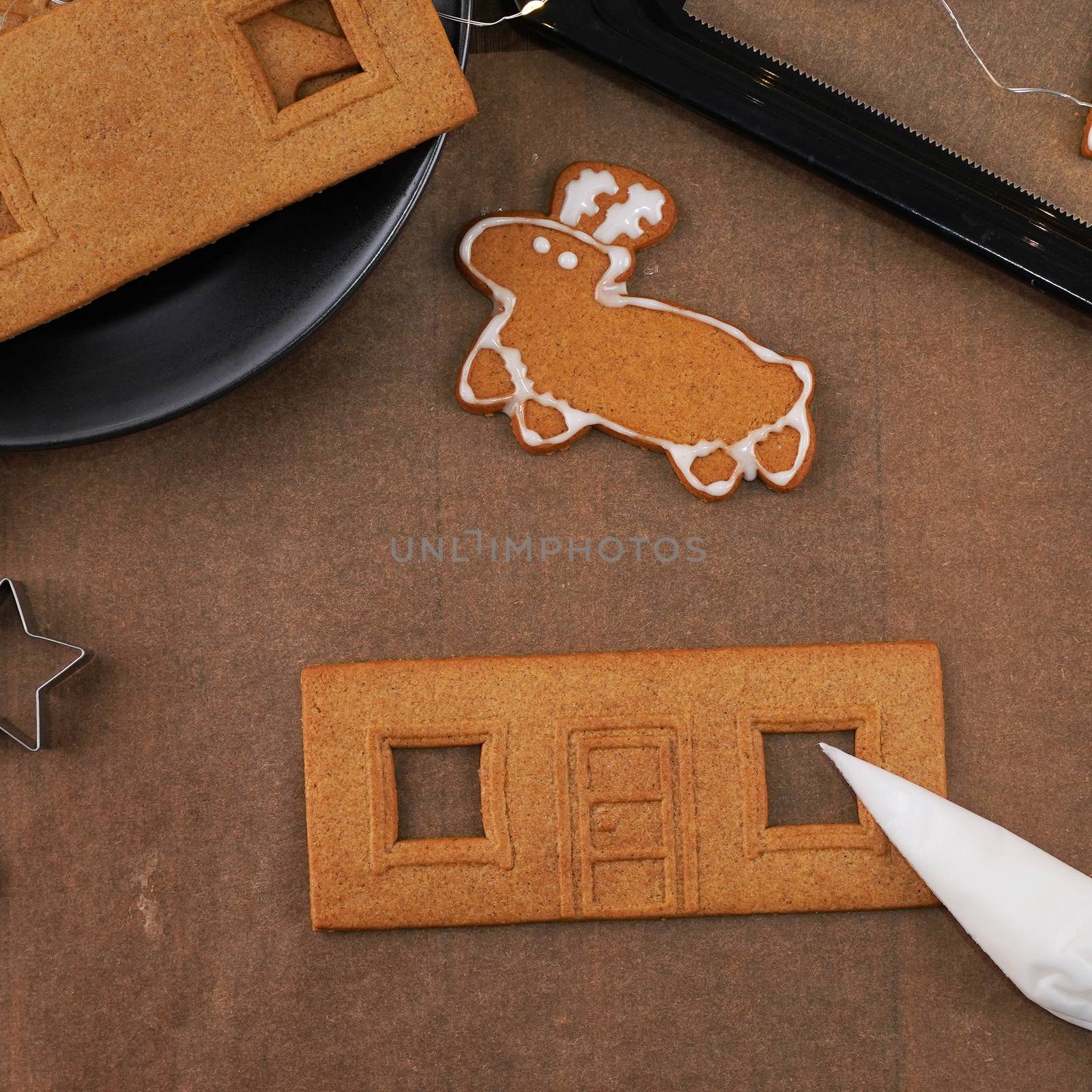 Young woman is decorating Christmas Gingerbread House cookies bi by ROMIXIMAGE
