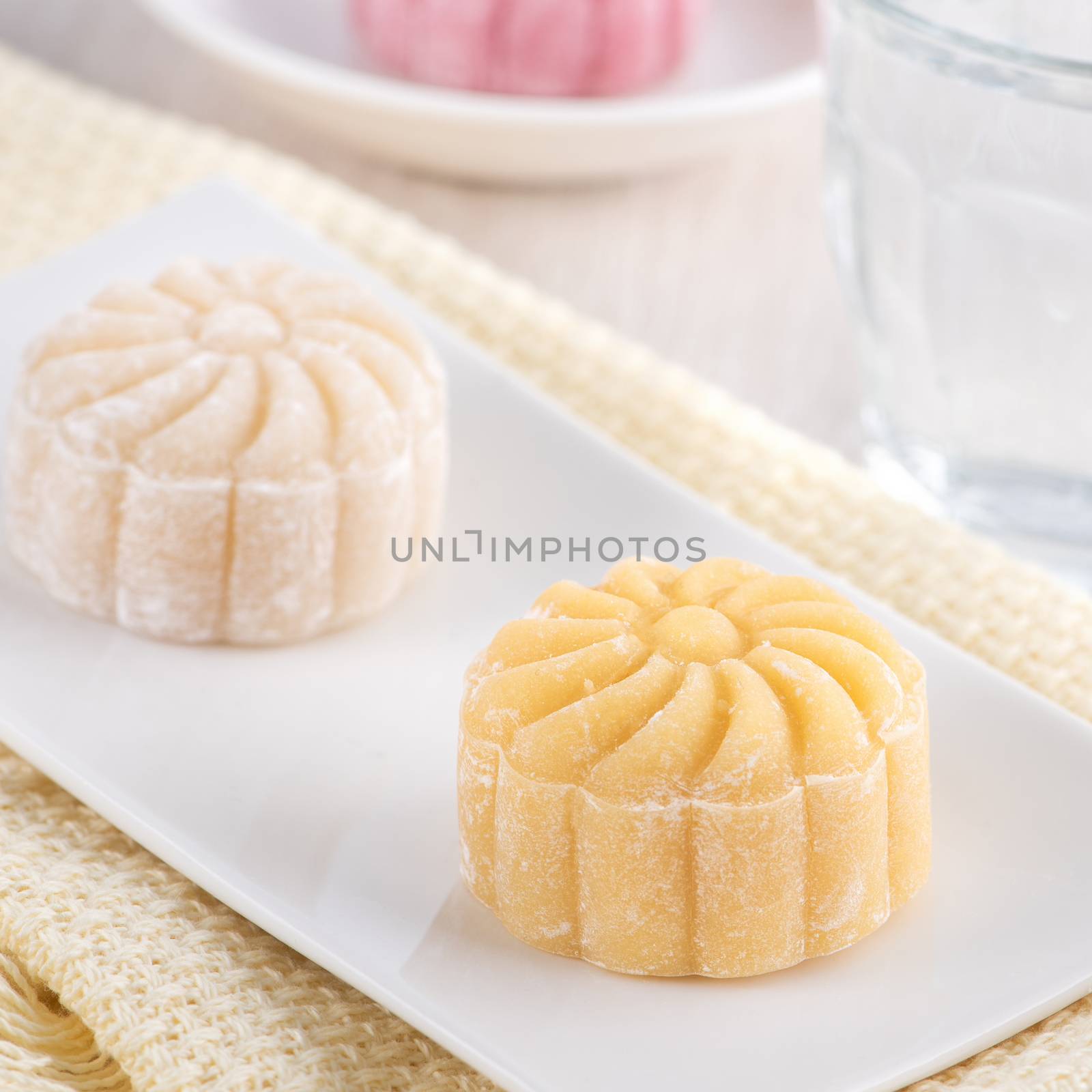 Colorful snow skin moon cake, sweet snowy mooncake, traditional savory dessert for Mid-Autumn Festival on bright wooden background, close up, lifestyle.