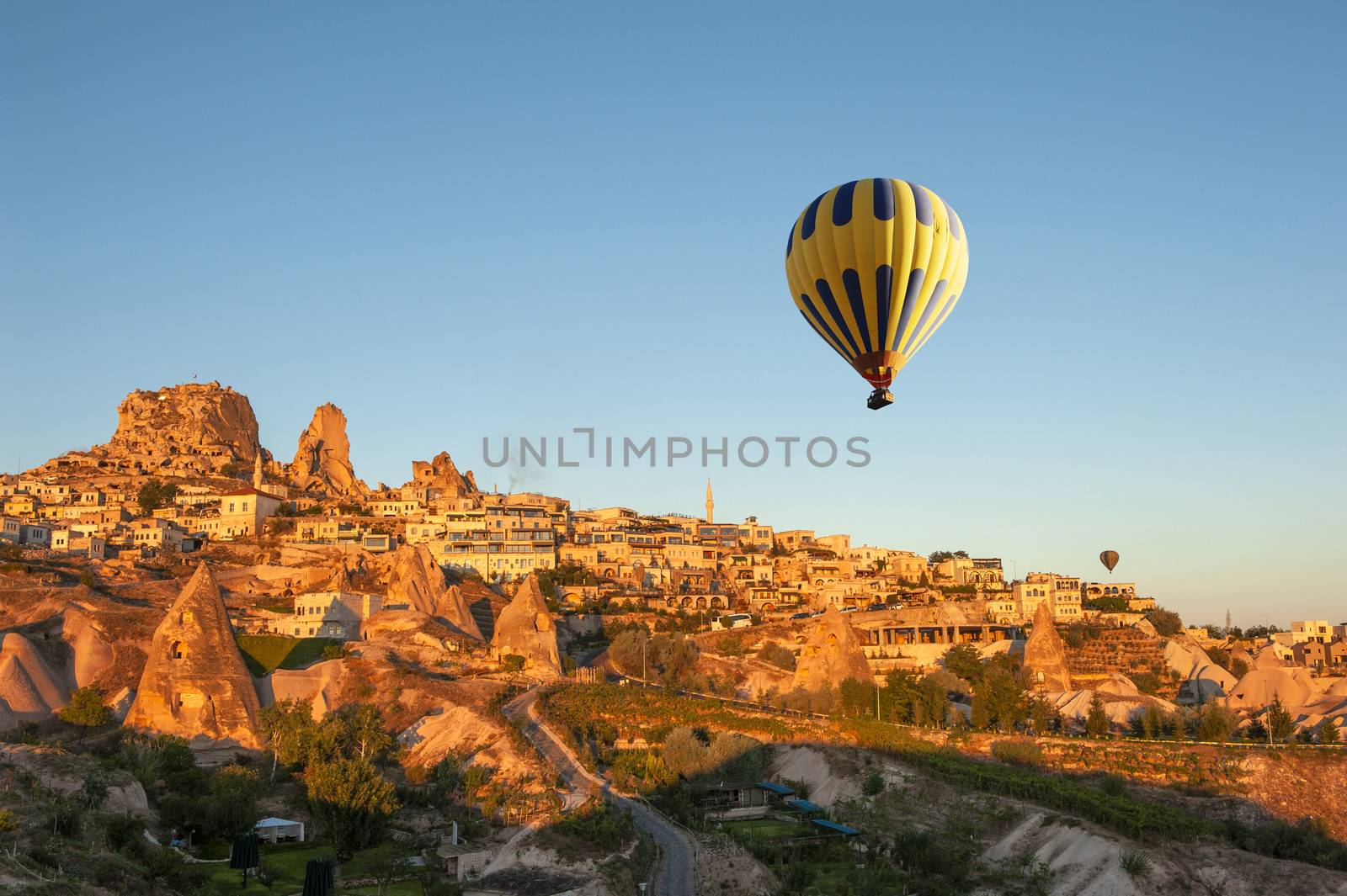 Hot air balloon is flying over Cappadocia near Uchisar castle at beautiful dramatic sunrise, Turkey