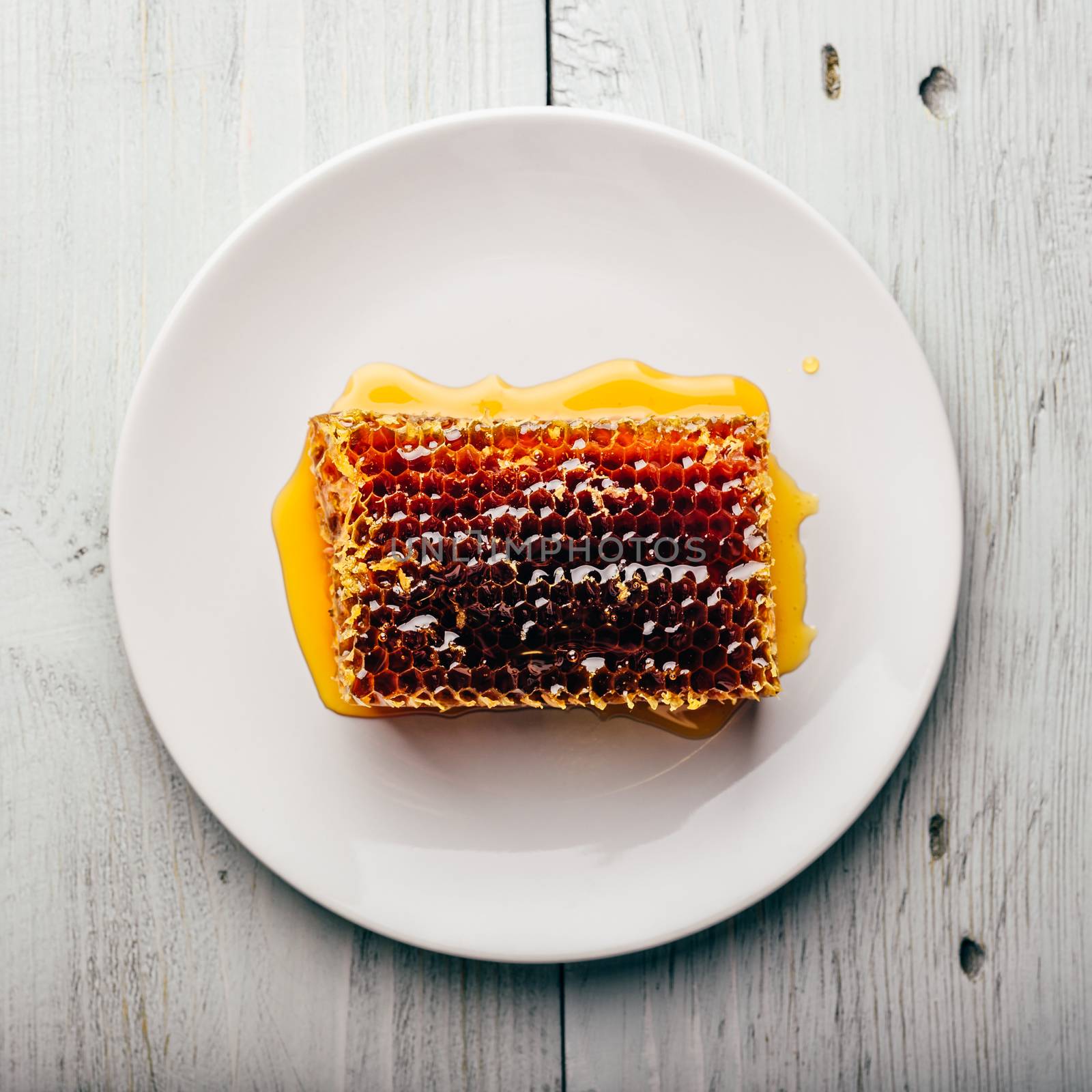 Top view of delicious yummy honeycomb on bright plate over light wooden background