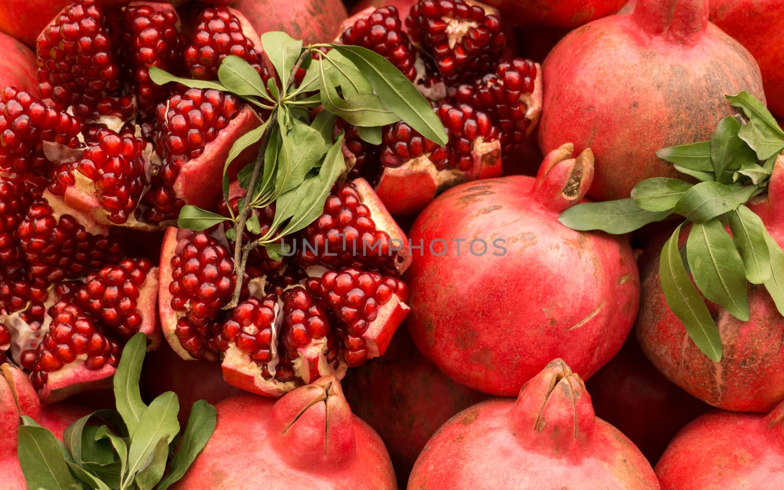 Ripe red pomegranates on the market. Cut pomegranates, herbs