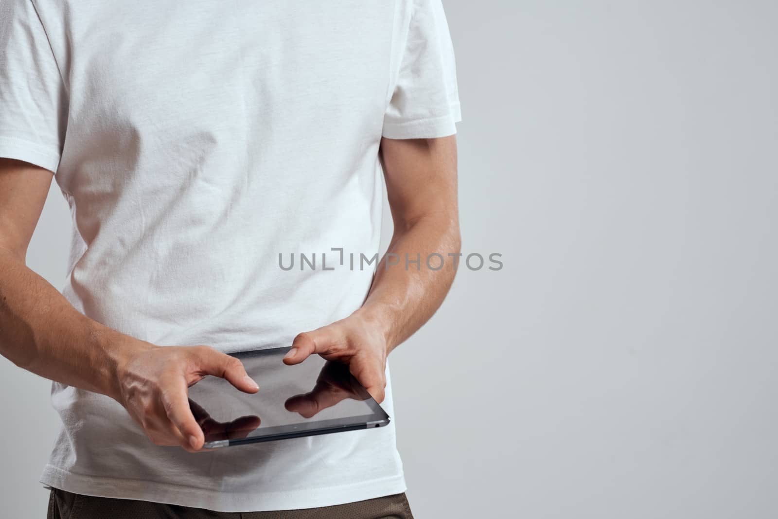 Tablet with a touch screen on a light background male hands white t-shirt cropped view by SHOTPRIME