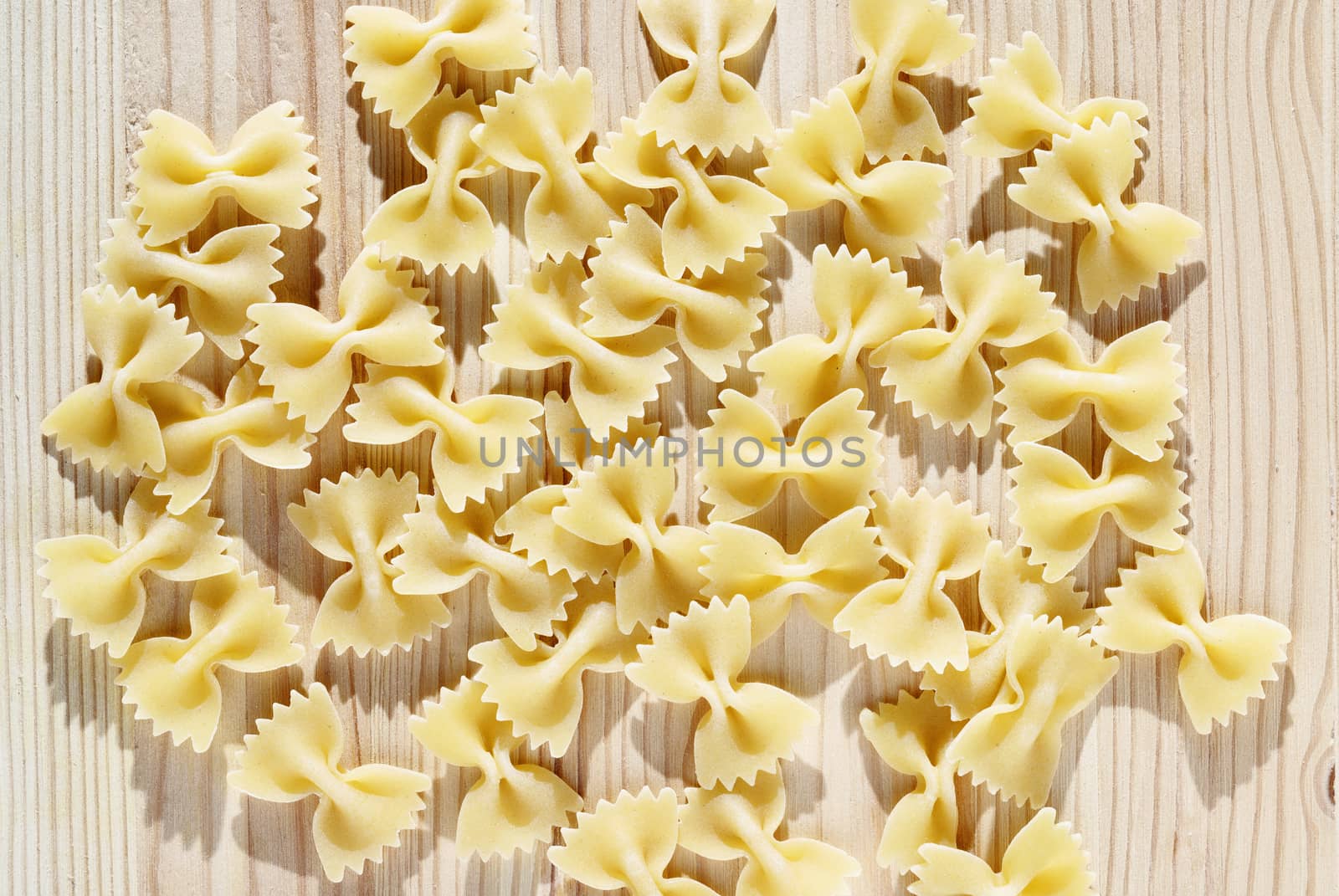 Dry pasta farfalle on wooden table , bow-tie pasta or butterfly pasta with two ruffled edges and the centre pinched together